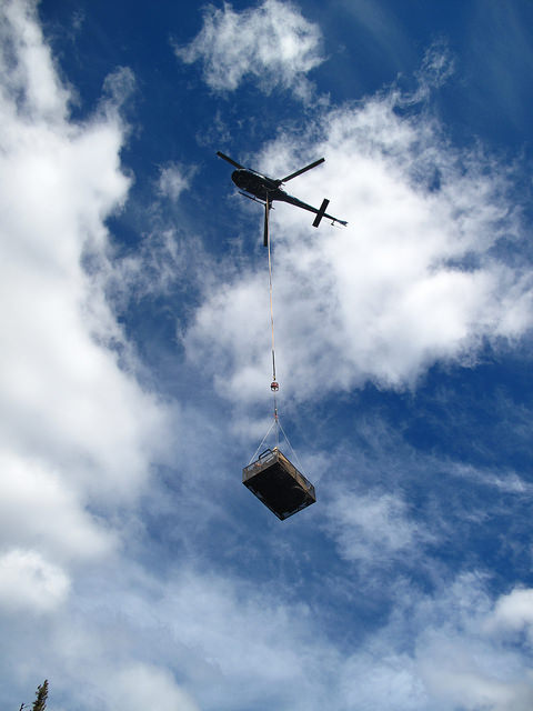 A helicopter uses a sling to move the drill equipment. 