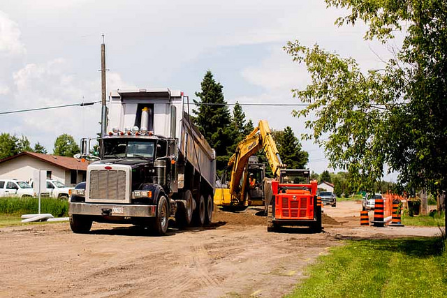 A dump truck, loader and small cat are all on a road at the Fort William First Nation housing project. 