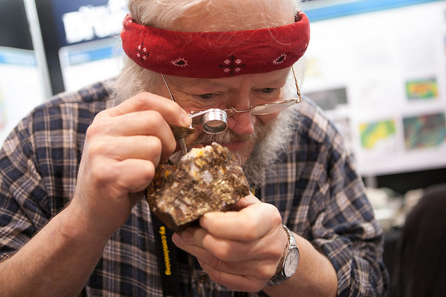 A man looking through a magnifying glass at a core sample.
