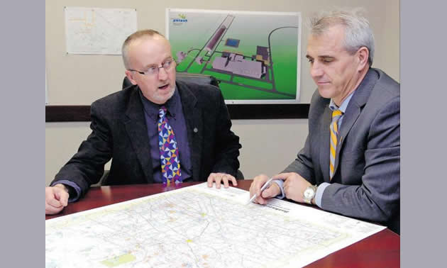 Two men sitting at a table looking at a map.