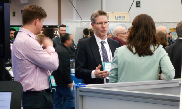 Gavin Dirom, the President and CEO of the AME, speaks with delegates at the TECK booth.