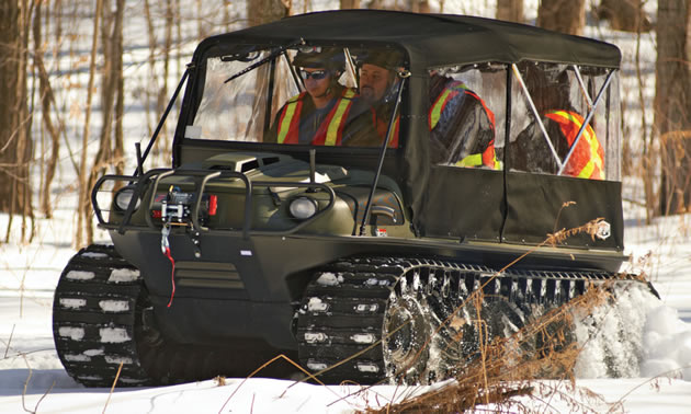 an all-terrain vehicle on tracks carrying workers over snow