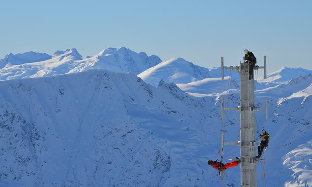 Shane Spencer, co-owner, has a background in mountain safety as well as construction, so he passes on his knowledge to his team. Here, the team is on a tall tower surrounded by snowy mountains.