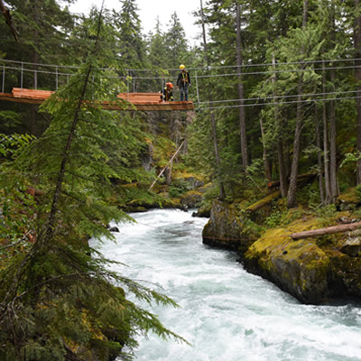 Axis Mountain Technical workers construct a suspension bridge over a river. 