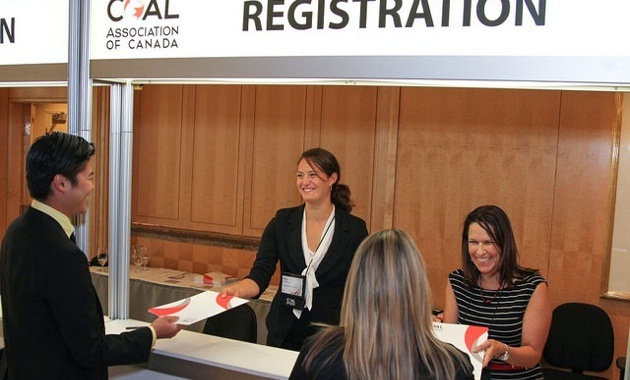 2 friendly looking CAC staff welcoming delegates with warm smiles. 