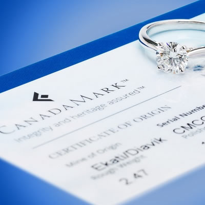 Canadamark certificate with diamond ring sitting on top of paperwork. 