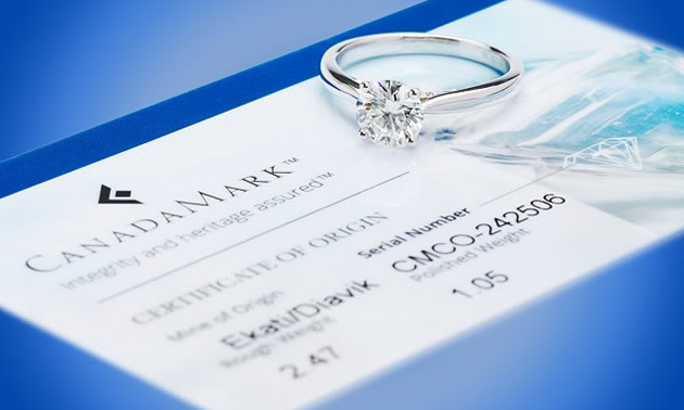 Canadamark certificate with diamond ring sitting on top of paperwork. 