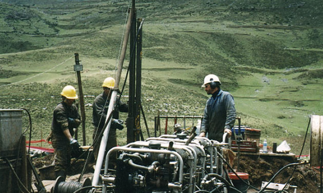 Group of workers using mining equipment in the field. 