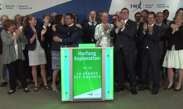Group of people standing at podium, smiling, clapping and congratulating each other. 