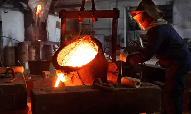 Worker pouring molten gold. 