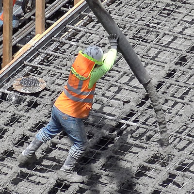 Worker pouring concrete onto steel girders. 