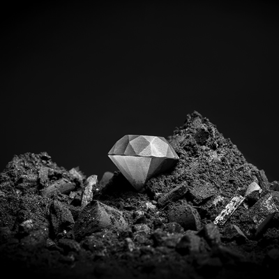A silvery-coloured diamond on a pile of dark, fine rock rubble 
