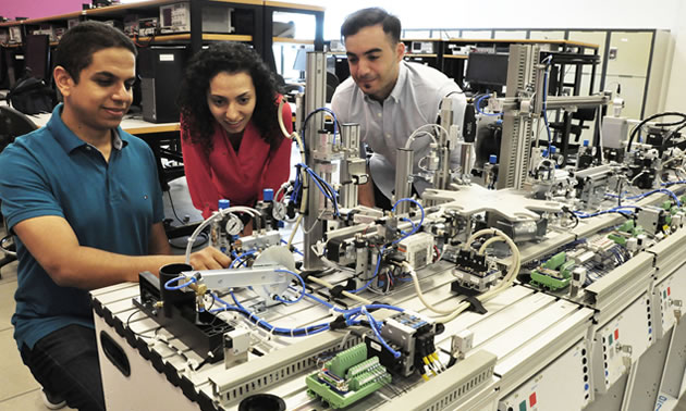 Instructor Amr Marzouk (L) shows new state-of-the-art industrial training assembly line equipment to students Anahita Mahmoodi and Mouataz Kaddoura. 