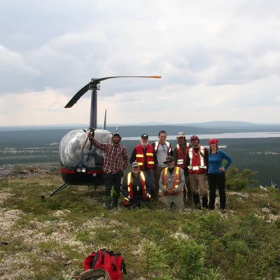 Stelmine Canada group shot, standing in front of a helicopter. 