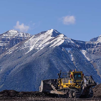 Scenic view of mountains, with worker and construction vehicle in foreground. 