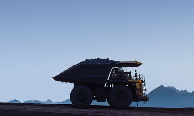 Silhouette of mining truck against blue sky. 