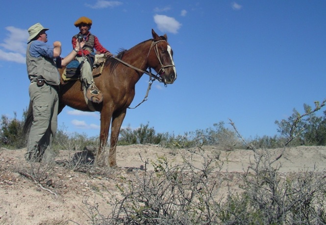 a man speaks with a young boy on horseback.