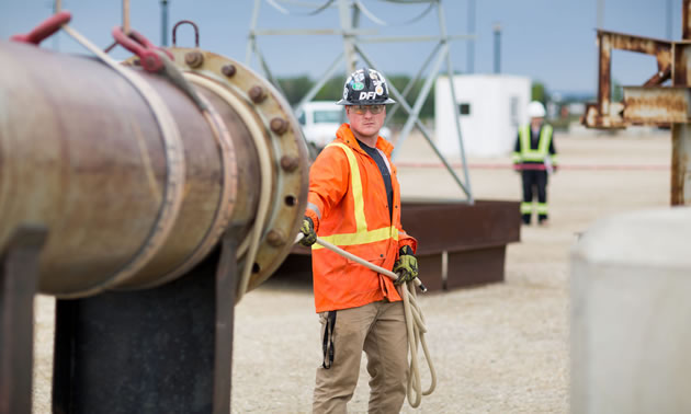 A young worker is standing by a pipeline. 