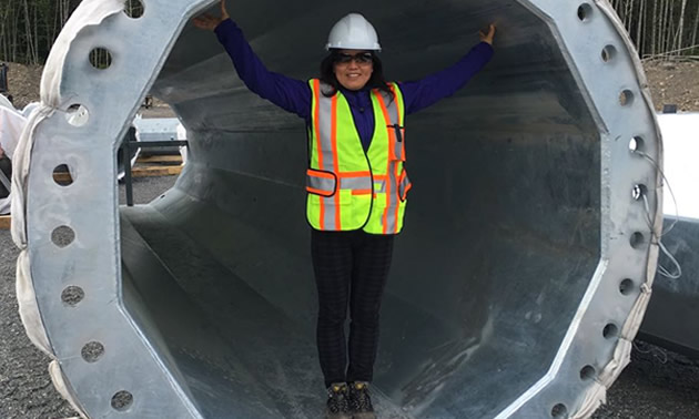 Alicia Du, general manager of HJT Steel Tower North America Co. Ltd., is standing inside a large steel cylinder.