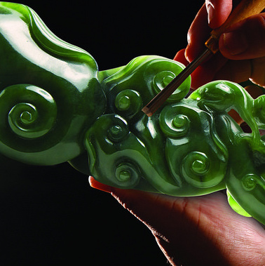 A close-up picture of a person's hand carving a piece of jade