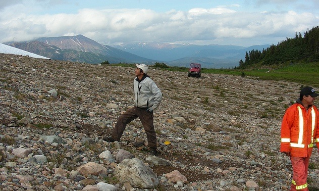 A man standing on the side of a rocky hill.