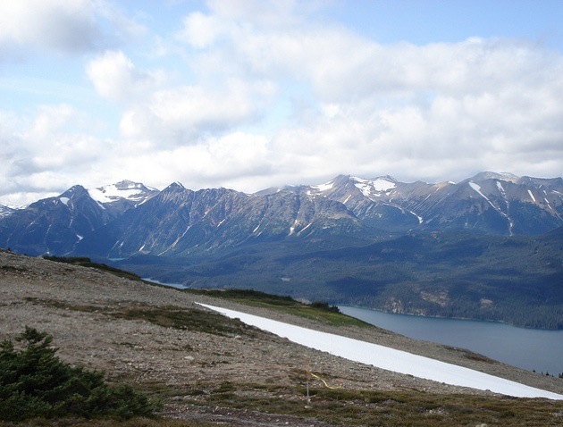 A photo of a possible new mining area, rocky slope in the forground, and a lake and mountains in the background. 