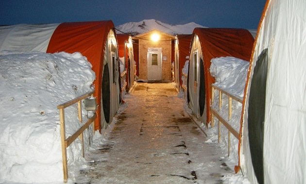 A photo of banks of snow against 4 long tents at the Selwyn Project camp. 