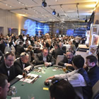 a crowd of well-dressed men and women around a casino card table