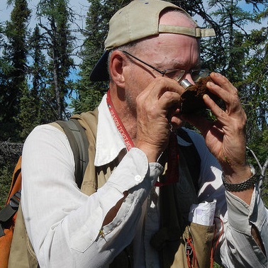 A man checking out an ore sample with a magnifying glass. 