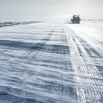 A mining truck on a barren, wintry stretch of road. 