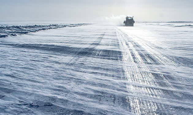 A mining truck on a barren, wintry stretch of road. 