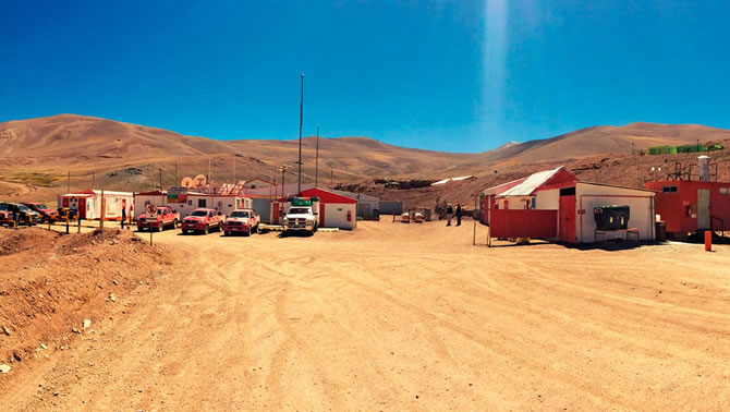 Photo of the El Morro project in Chile, showing a blue sky, desert landscape and trucks in the foreground of the picture. 