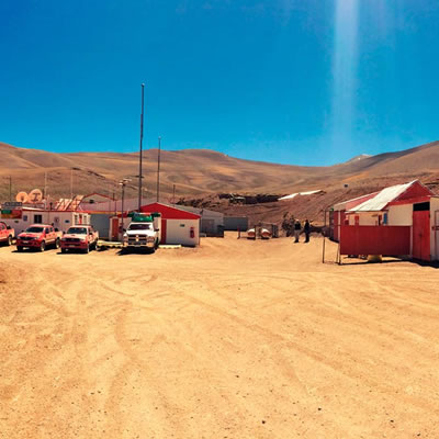 Photo of the El Morro project in Chile, showing a blue sky, desert landscape and trucks in the foreground of the picture. 