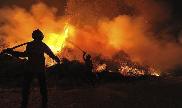 A silhouette of a firefighter in front of a blaze.