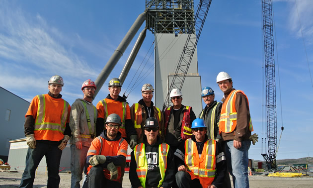 a group of people posed in two rows with hardhats and safety vests