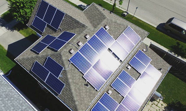 Birds-eye view of top of house equipped with solar panels. 