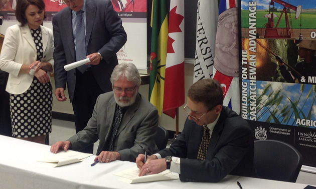 Executive director Rodney Orr and board director David Grier sign the funding agreement for University of Saskatchewan mining classes on June 21, 2013. 