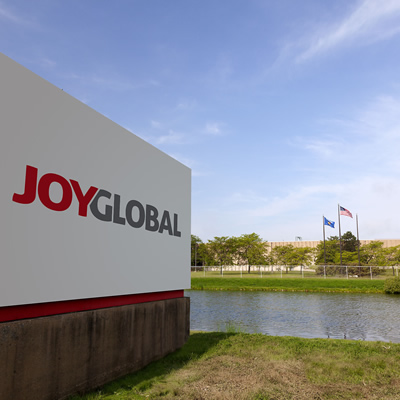 Sign of Joy Global, with lake in foreground and flags on the distant bank. 