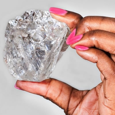 Picture of a woman holding a large 813 carat diamond. 