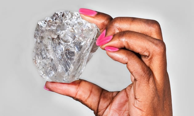 Picture of a woman holding a large 813 carat diamond. 