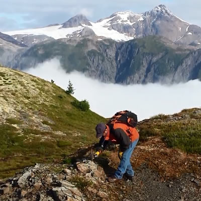 A geologist examining rocks on a mountainside. 