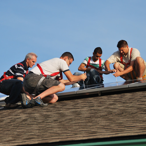 Four men on a roof working on an equipment installation.