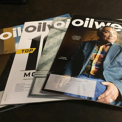 A number of Oilweek magazines spread out on a table. 