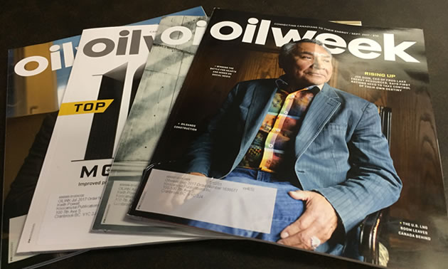 A number of Oilweek magazines spread out on a table. 