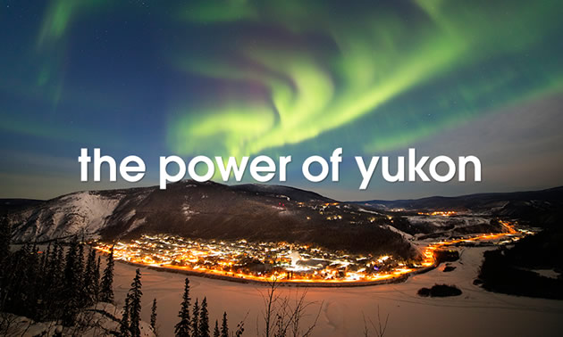 'Power of the Yukon' text, with picture of light-up town at night and aurora borealis in sky.  