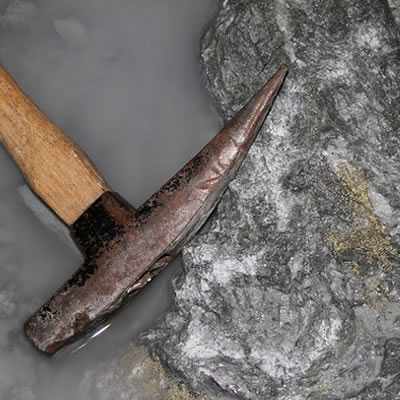 A picture of a gold prospector's pickaxe and a rock with veins of gold in it. 