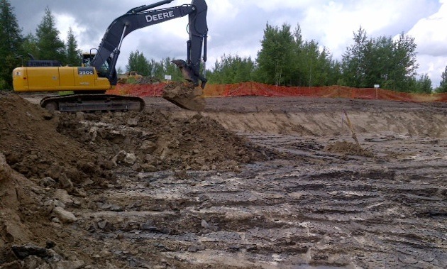 A backhoe digging at a Rainy River test pit. 