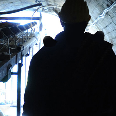 Silhouette of man standing in mine tunnel. 