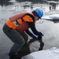 Photo of person in the icy water of slurry spill