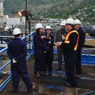 A group of people wearing hard hats and coveralls stand overlooking Teck's smelter operations